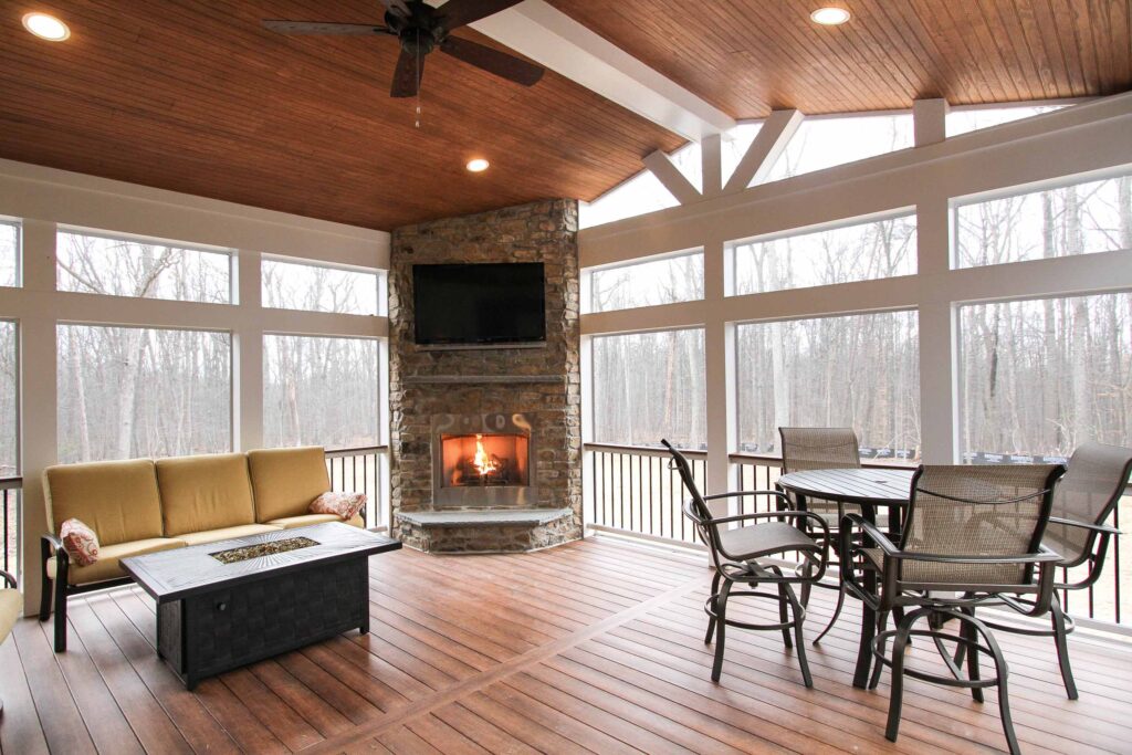 Screened-in porch with stone fireplace, wood ceiling, and energy-efficient design in a Net Zero custom home