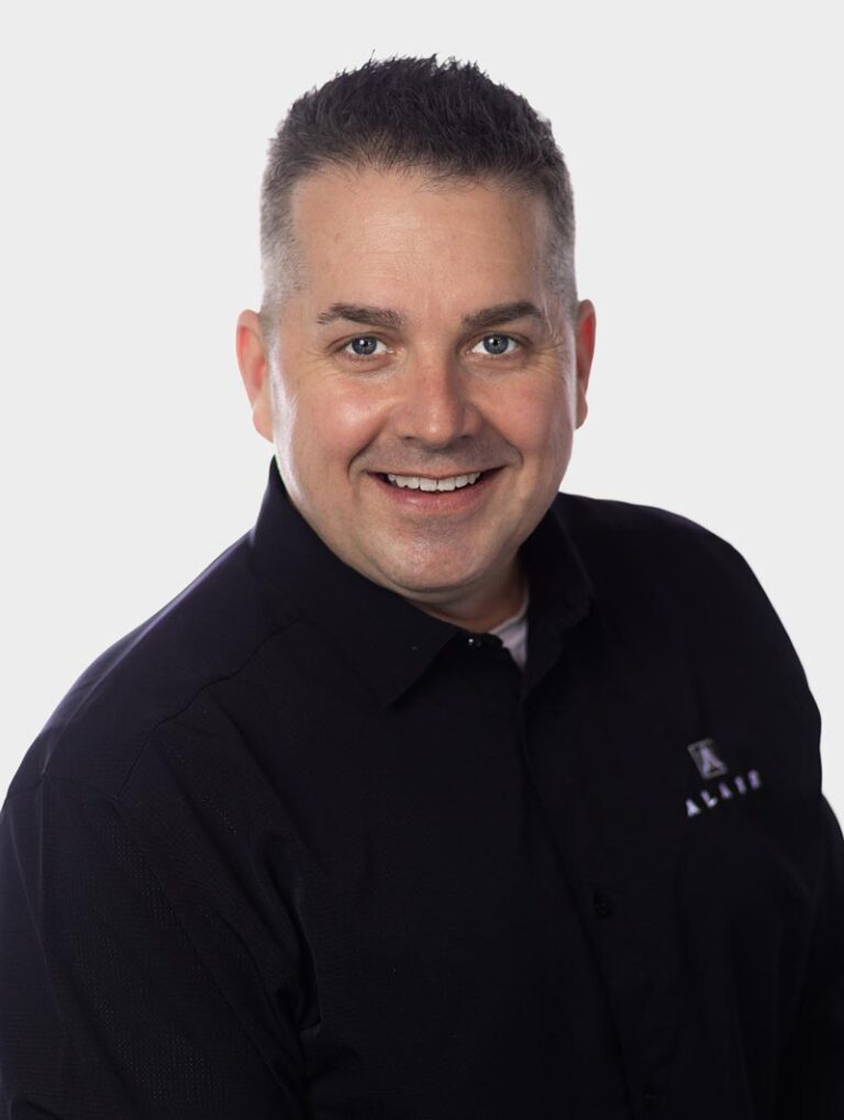 Adam McCaa, Director of Sales at Alair Homes. Wearing an Alair Homes shirt against pewter background.