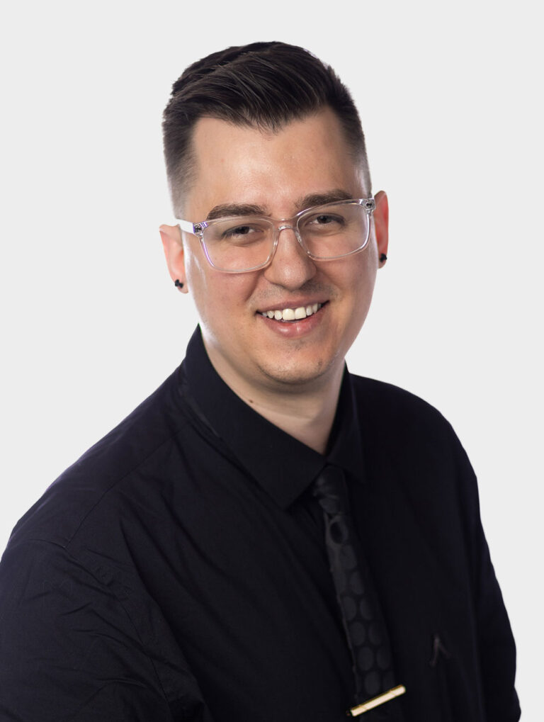 Paul Leszczynski, Director of IT at Alair Homes. Wearing a black shirt against pewter background.