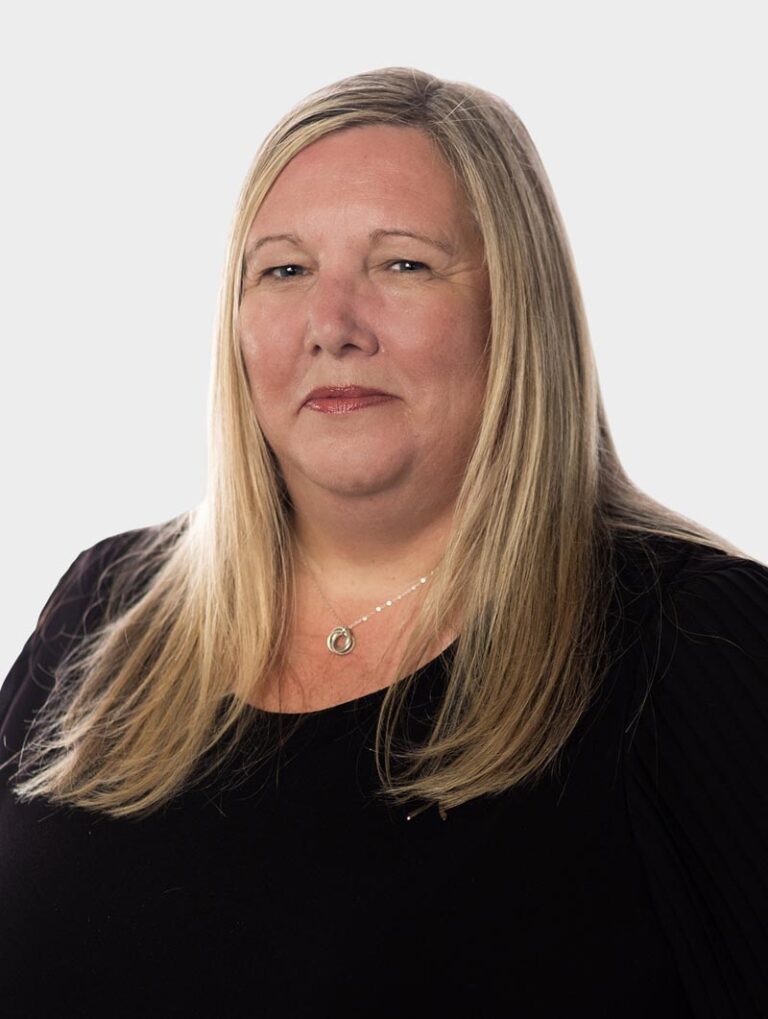 Rachel Peace, Internal HR at Alair Homes, wearing black, posing against pewter background.