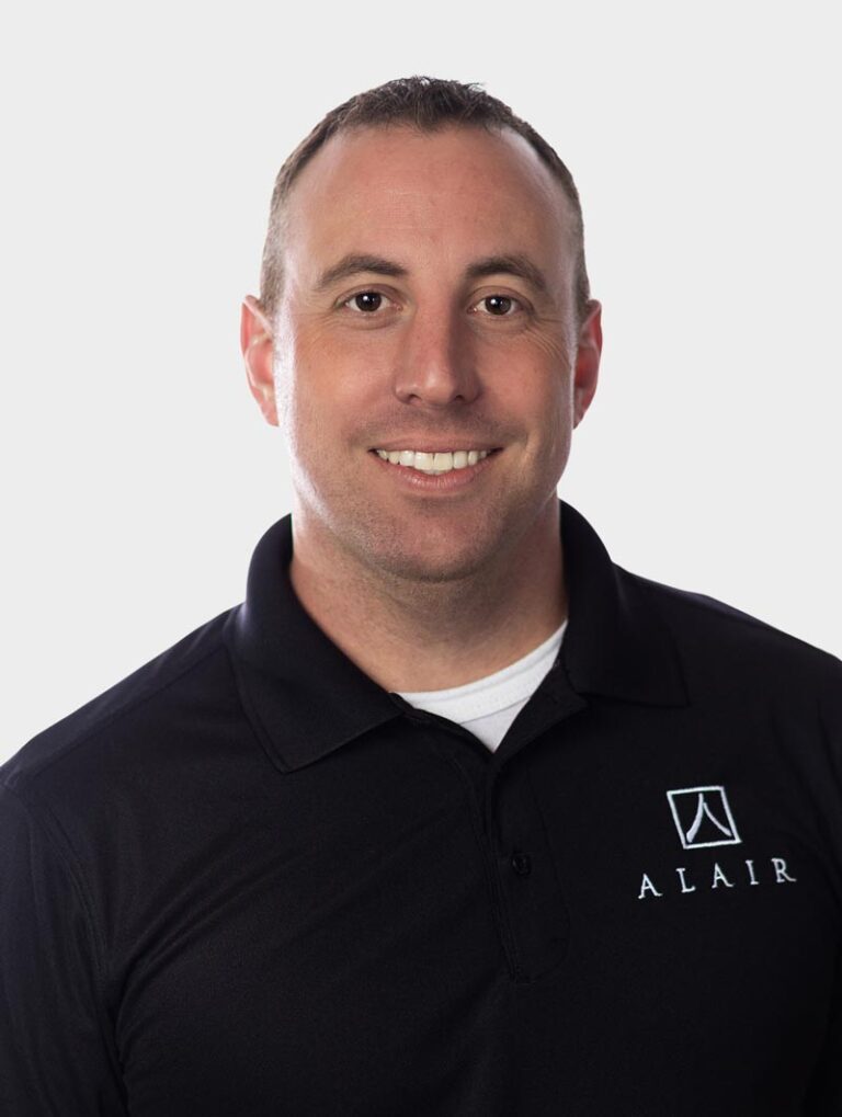 Man wearing a dark coloured Alair Homes shirt against pewter background.