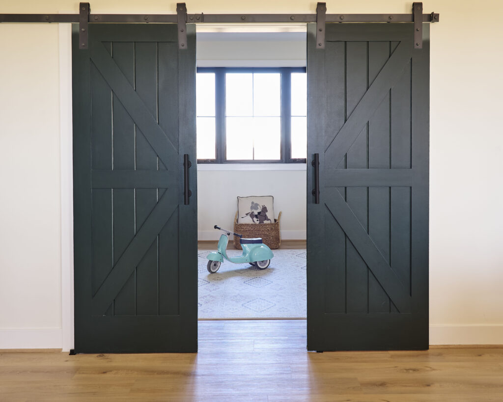 Multi-purpose children’s playroom and study area with sliding barn doors, designed for flexible learning and storage in a custom home