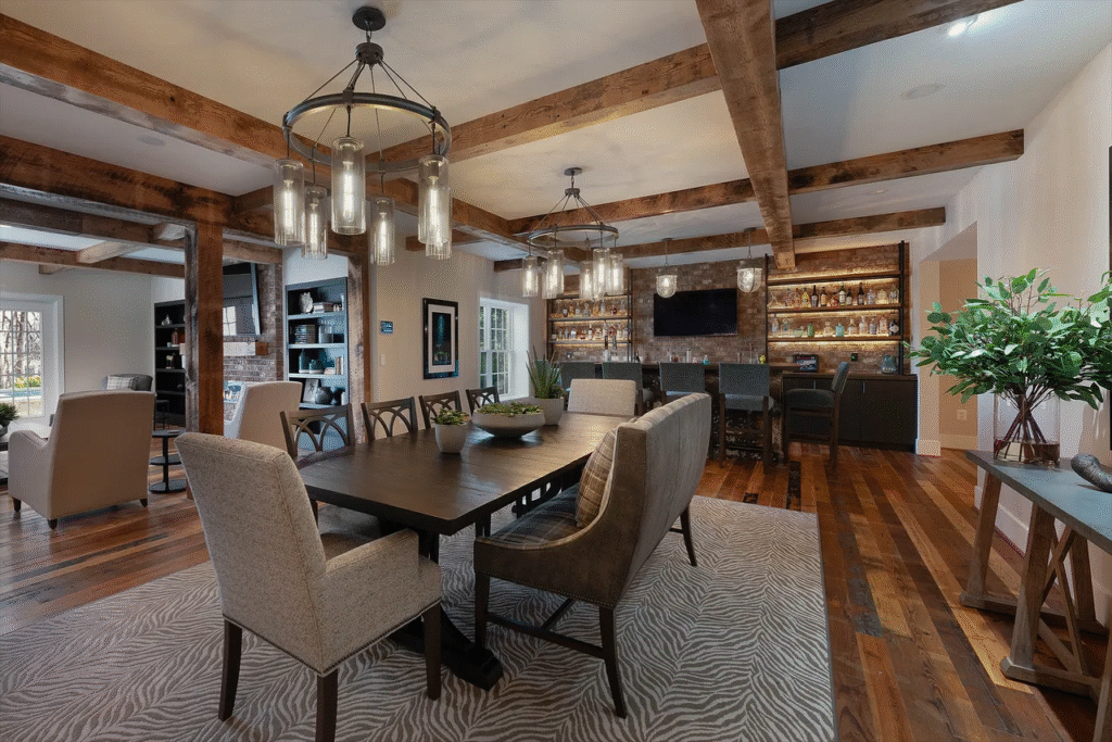 Rustic character dominates with exposed brick walls, heavy wood beams, and wide-plank flooring but modern furnishings and layered lighting blend old and new.