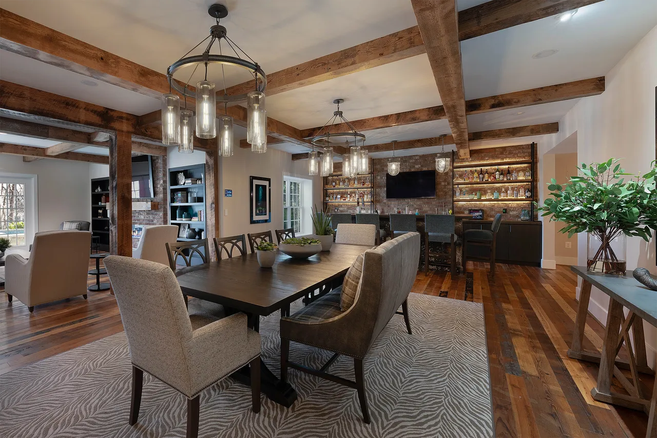 Rustic character dominates with exposed brick walls, heavy wood beams, and wide-plank flooring but modern furnishings and layered lighting blend old and new.