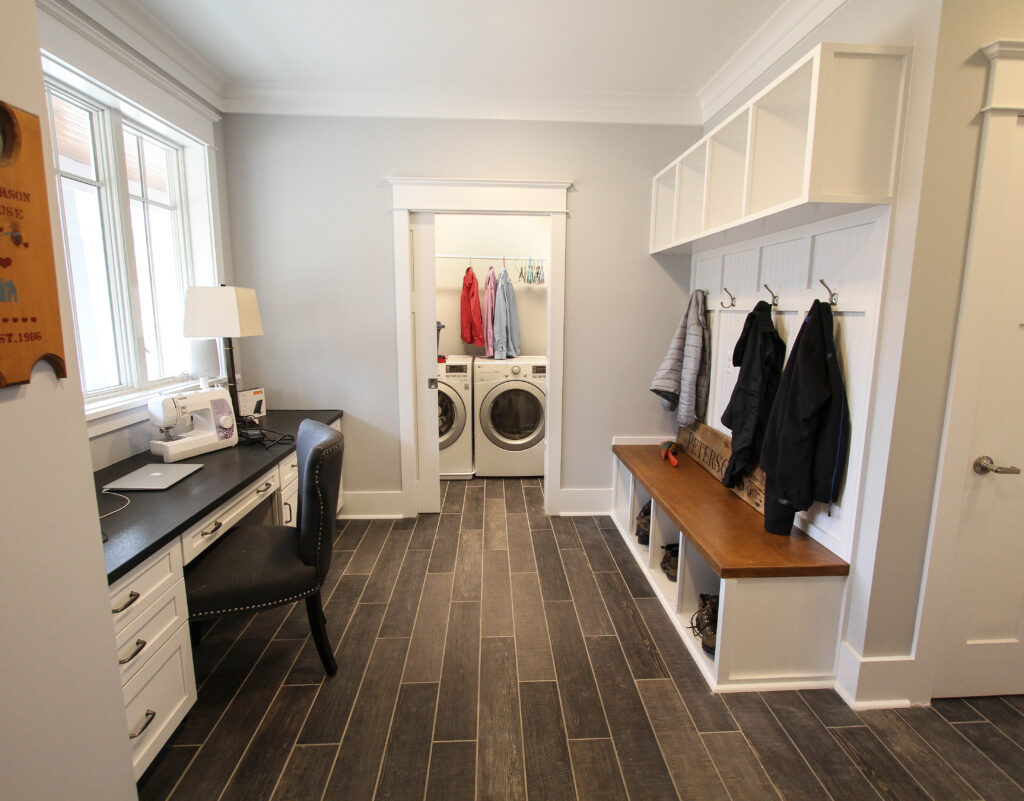 Mudroom with built-in storage lockers and office desk with shelves leading into a laundry room