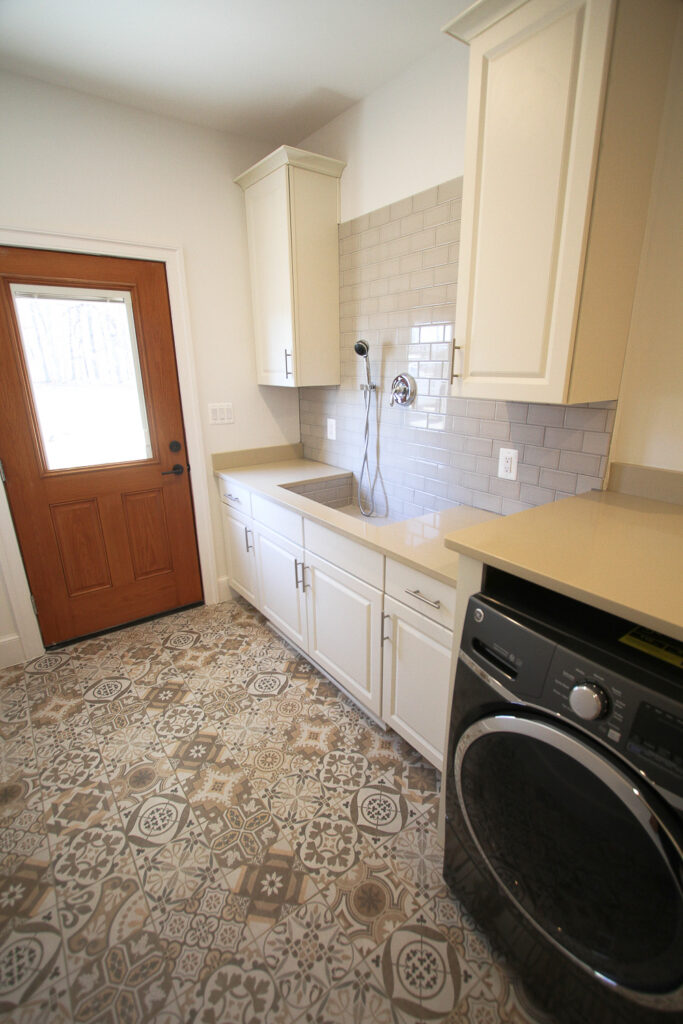 Pet-friendly mudroom with dog shower, built-in kennel design, and laundry