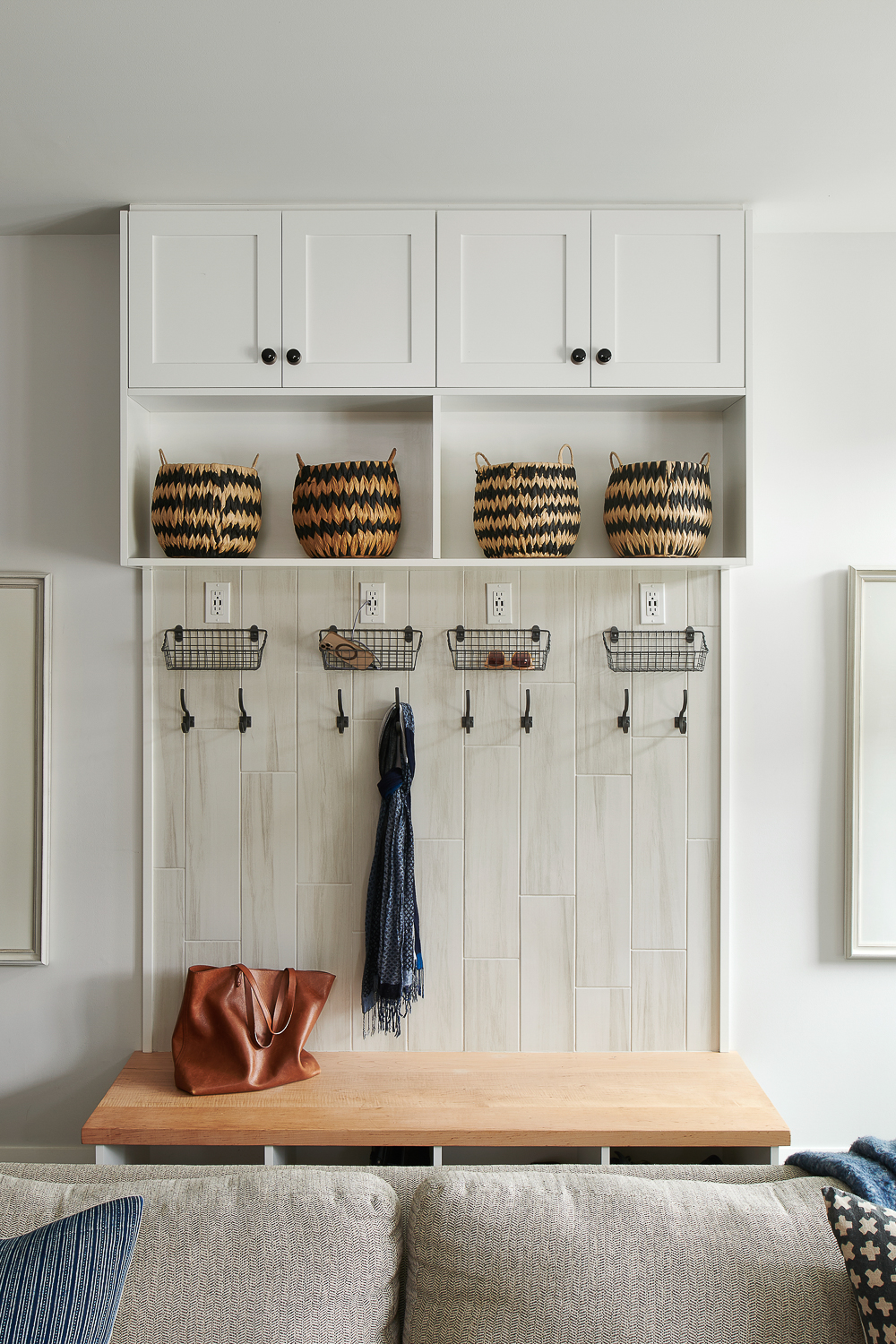 White mudroom with hooks and basket storage.