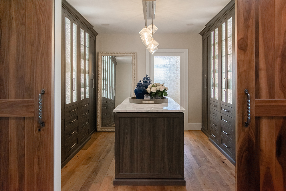 Sliding barn doors and wide-plank wood floors set a rustic tone, while sleek cabinetry with modern hardware and a marble-topped island introduce elegance and organization.