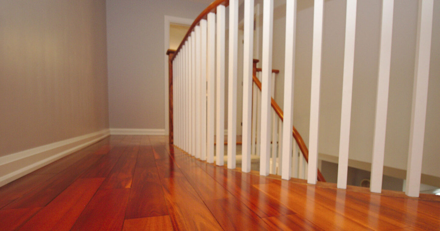 close up of cherry stained luxury vinyl flooring and with banisters leading downstairs