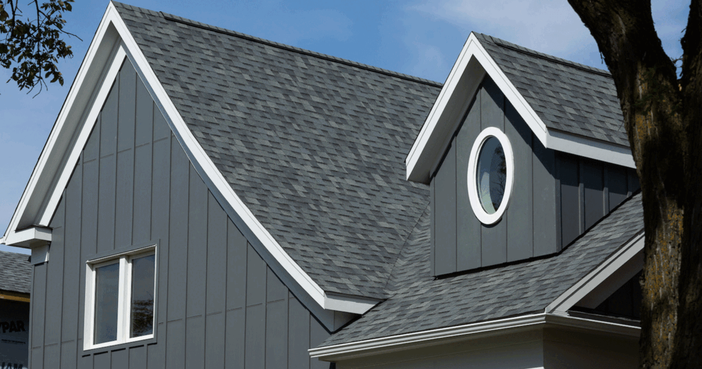Close up of exterior of top of grey custom home with white trim