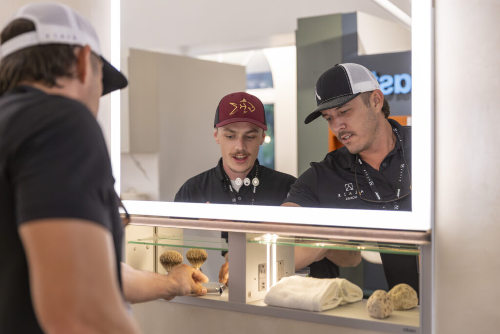 Three project managers examine brushes and towels at the Kohler product showcase.