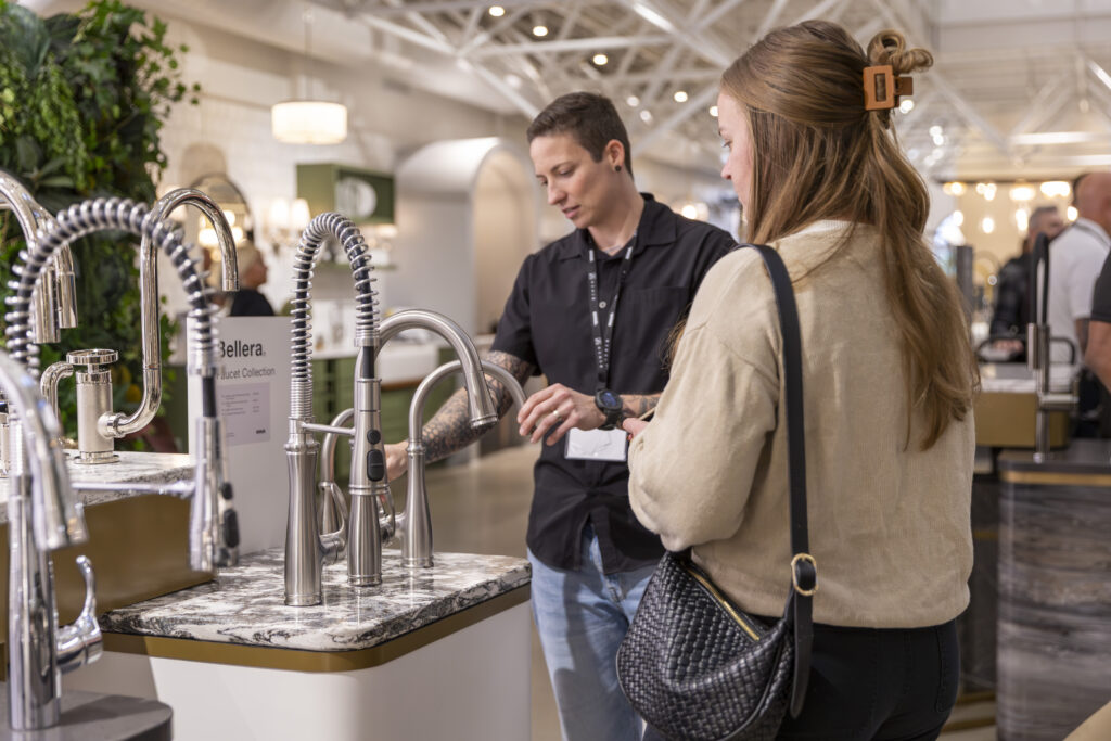 Two project managers examine sink faucets at Kohler product showcase