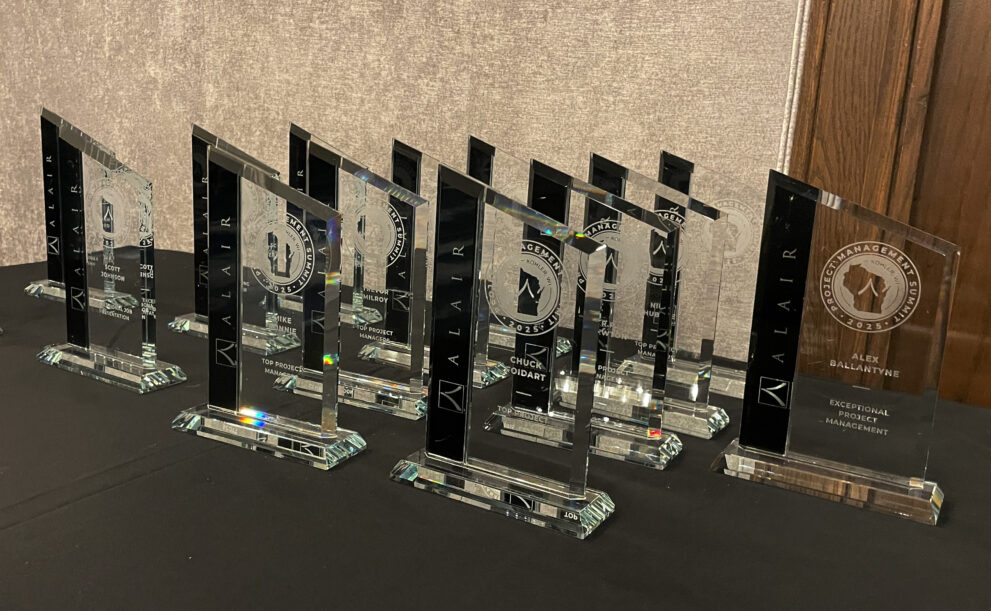 A row of crystal award trophies on a table for the Alair PM Awards.