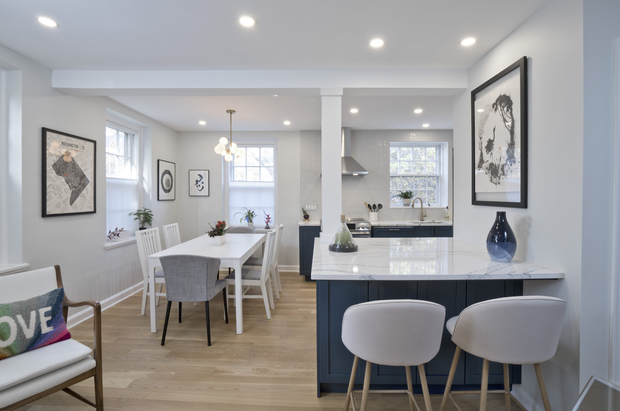 Kitchen island with two stools and an open dining space with a white kitchen table.