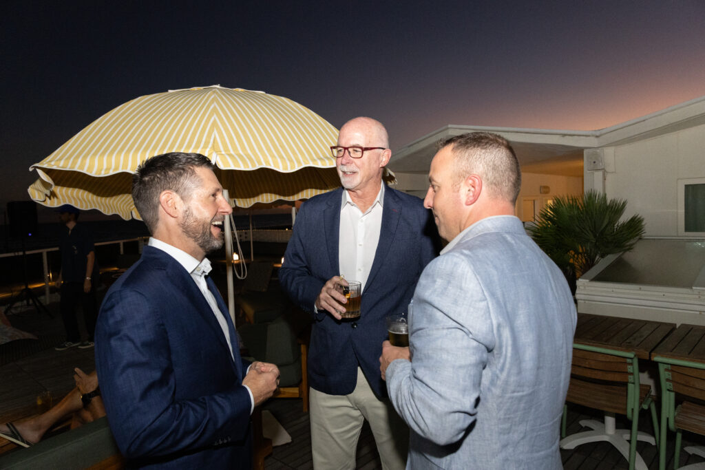 Nighttime shot of the Alair Galveston launch party with three guests mingling