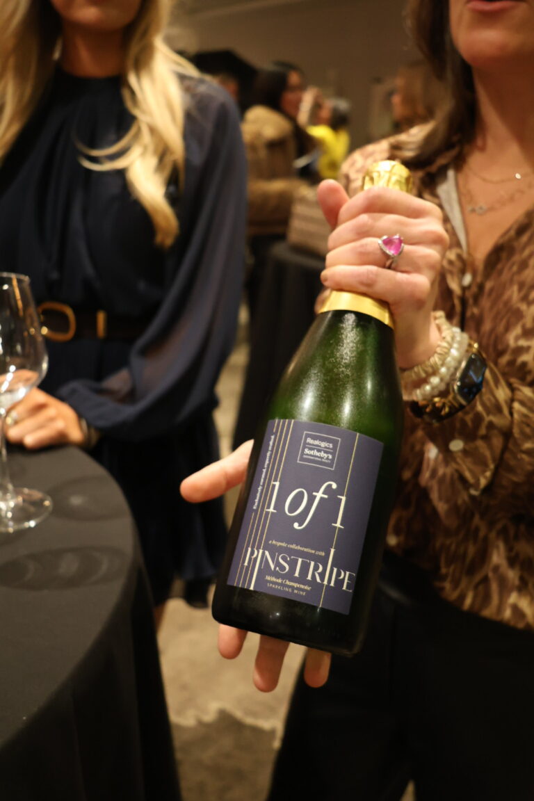 a woman holding up a bottle of pinstripe sparkling champagne
