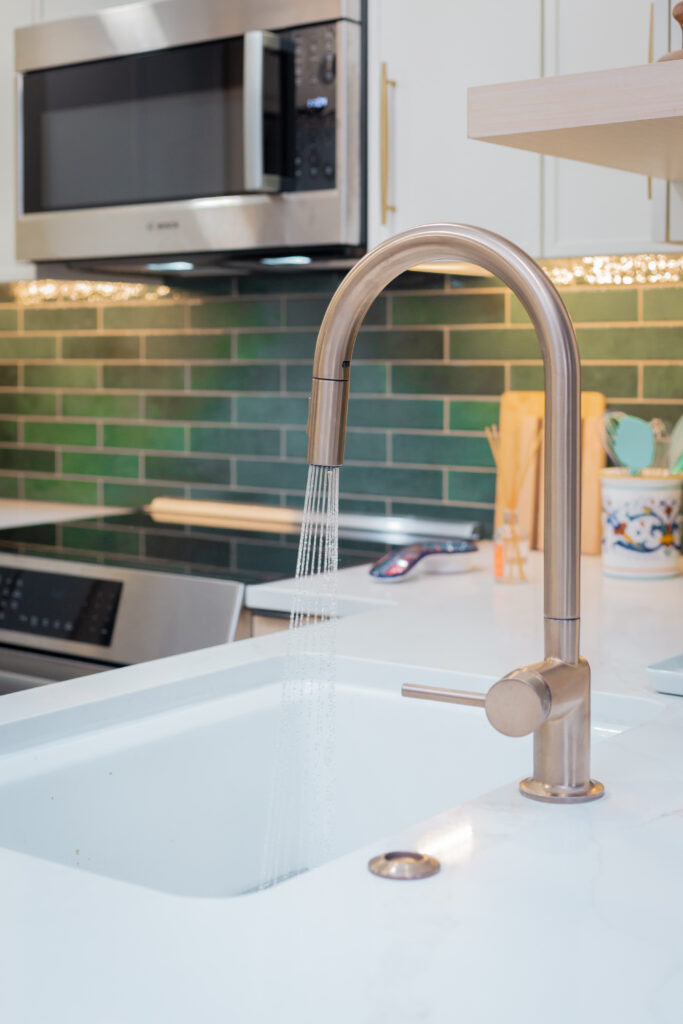 Running faucet with white quartz countertops on a peninsula island.