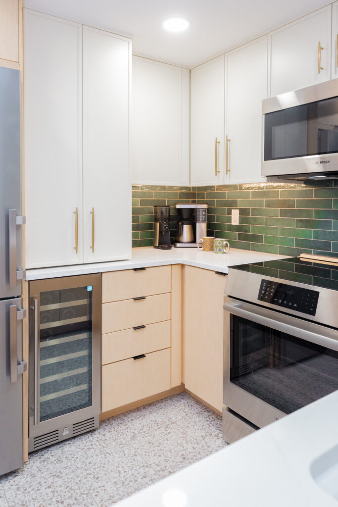 Close up of light wood cabinetry with a stainless steel wine cooler in a remodeled condo kitchen.