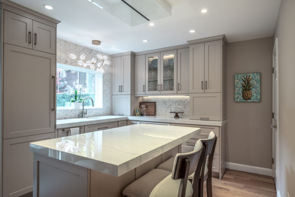 Elegant custom kitchen with oversized island, integrated storage, herringbone tile backsplash, and light-filled design ideal for entertaining.