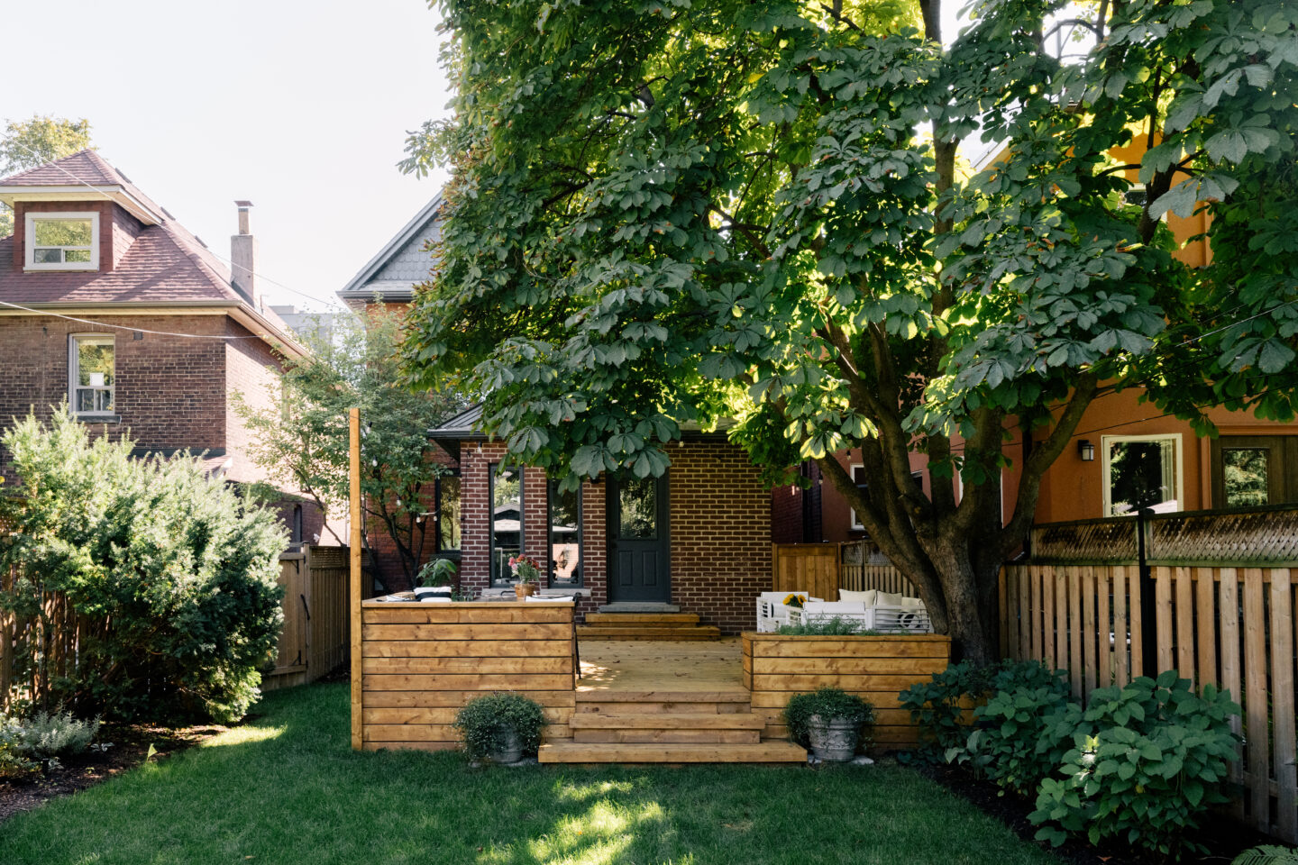 Wooden deck with large tree in backyard.