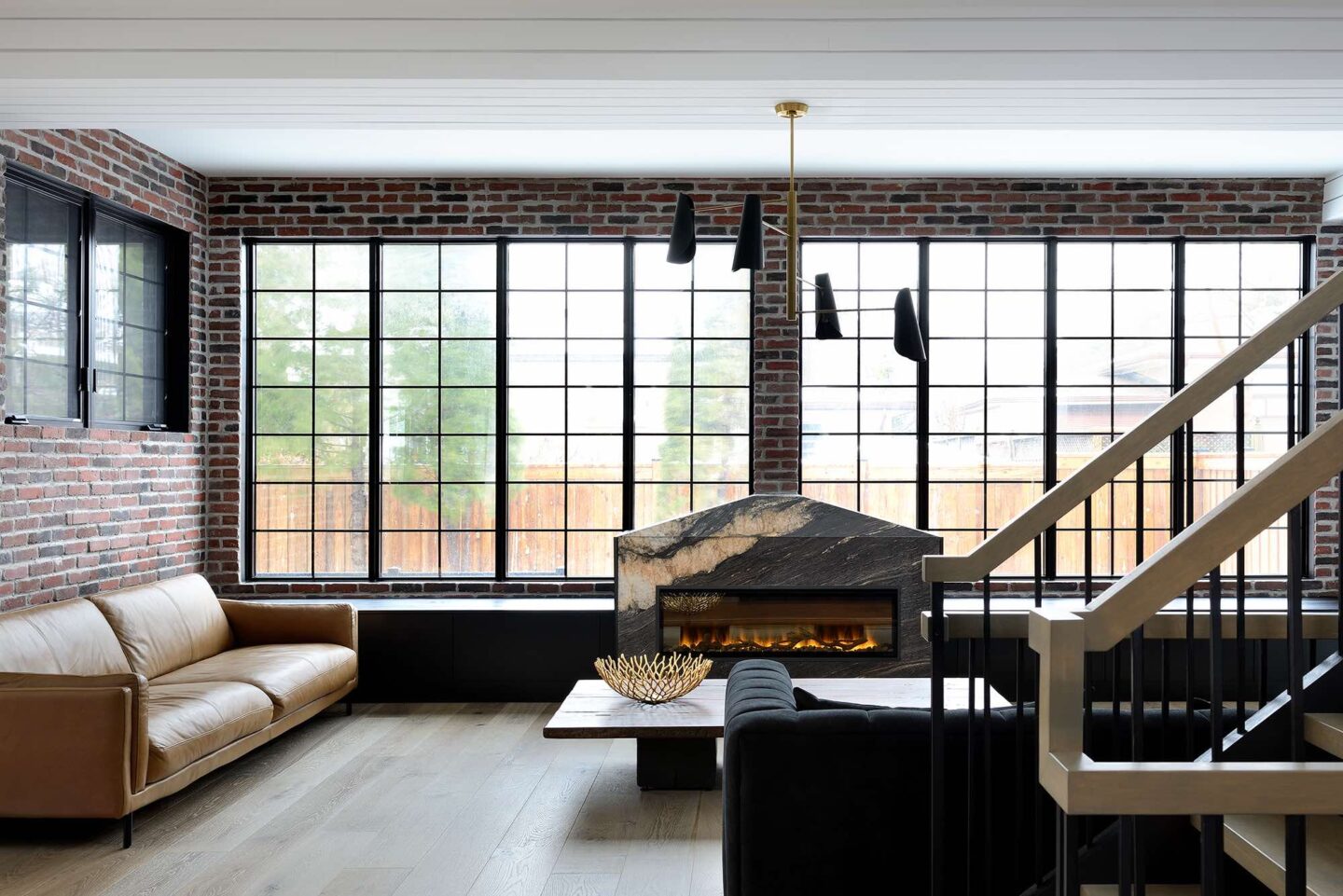 Industrial-modern custom home in Barrie, Ontario featuring exposed brick walls, black-framed windows, and contemporary fireplace design