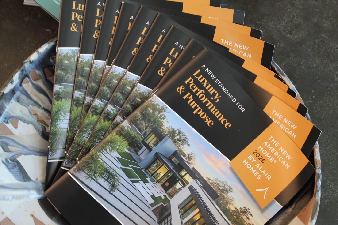 A fanned stack of lookbooks of The New American Home® 2026 by Alair Homes
