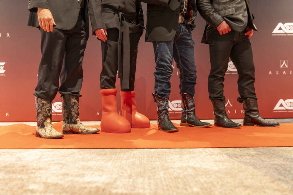 Four Alair partners show off their boots during the creative black tie event, including three cowboy boots and one big red boot pair (second from left).