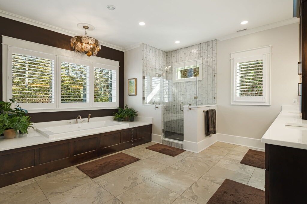 Spacious custom bathroom with soaking tub, glass shower, dark wood vanity and large tile flooring