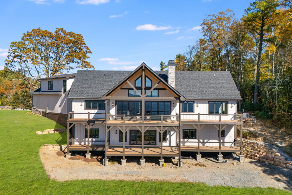 Rear exterior of custom mountain home with large covered deck, modern siding and wooded setting