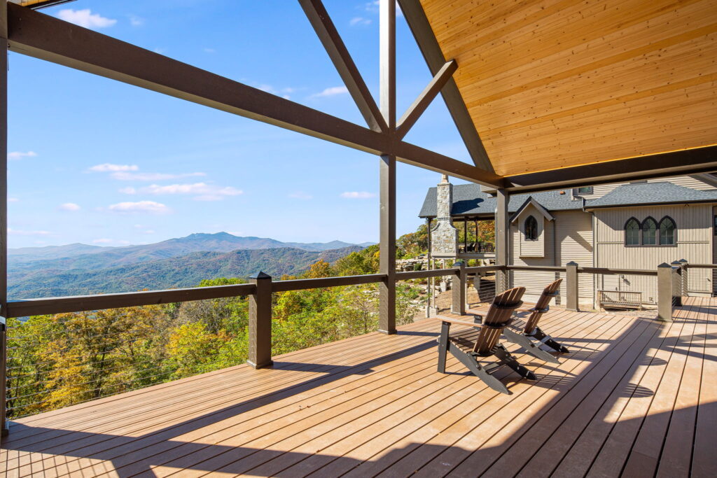 Covered deck with seating overlooking mountain views, featuring wood beams and railing detail