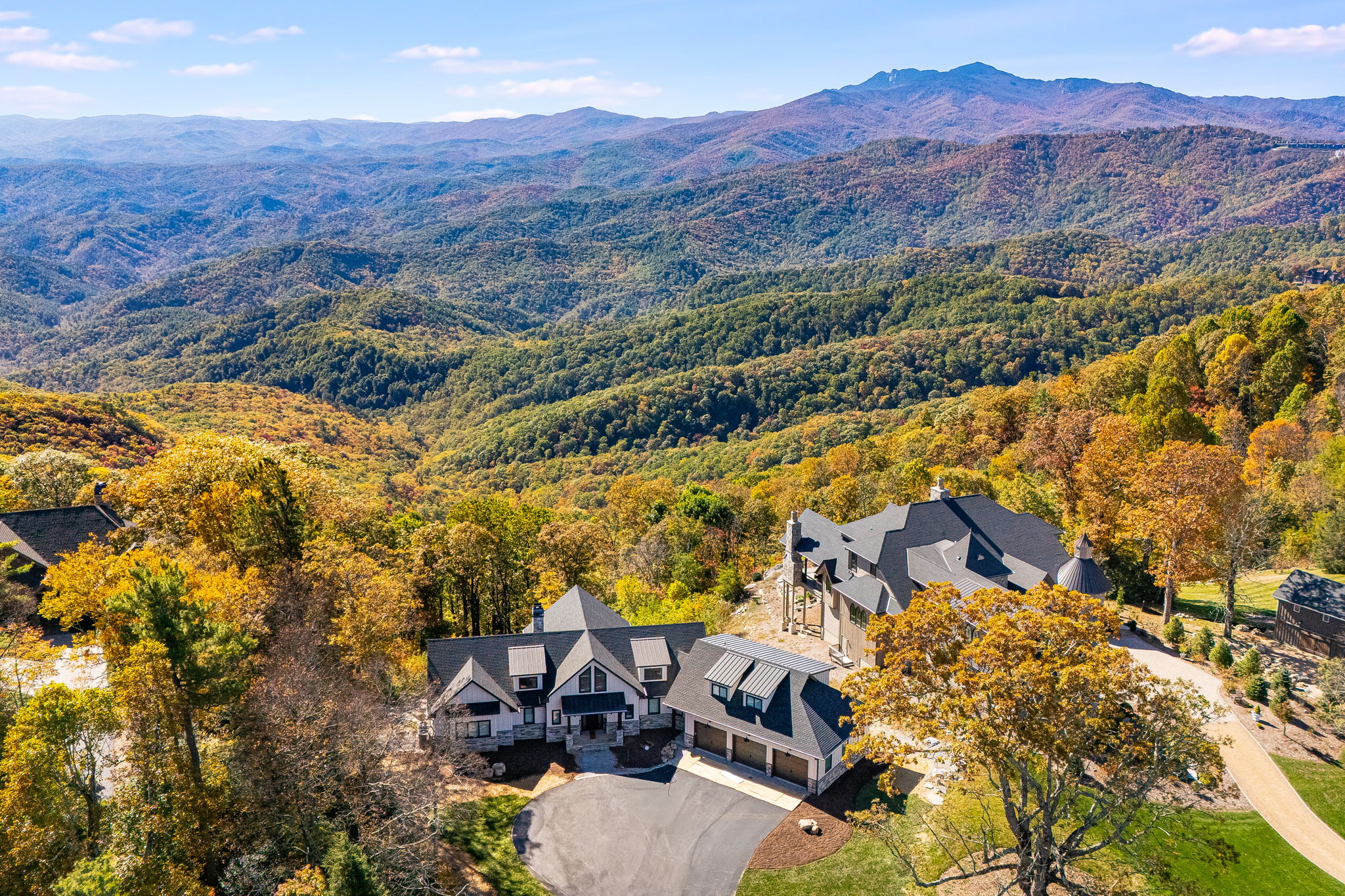 Aerial view of custom mountain home surrounded by forest with wide scenic mountain views