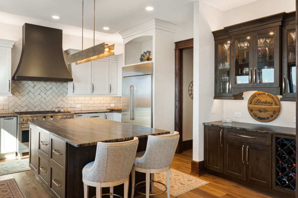 Modern kitchen with dark wood island, white cabinets, black range hood and built-in bar storage