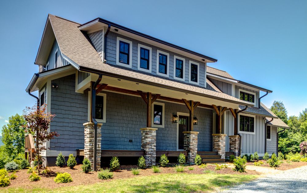 Front exterior of a custom High Country home featuring stone columns, covered porch, and modern mountain architecture.