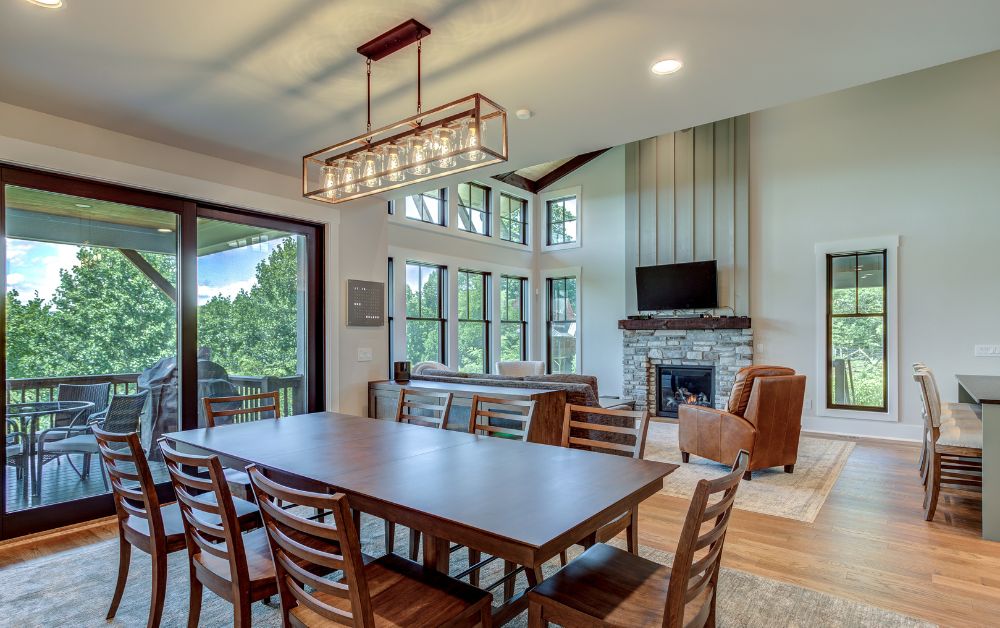 Open-concept living and dining area with vaulted ceilings, stone fireplace, and mountain views.