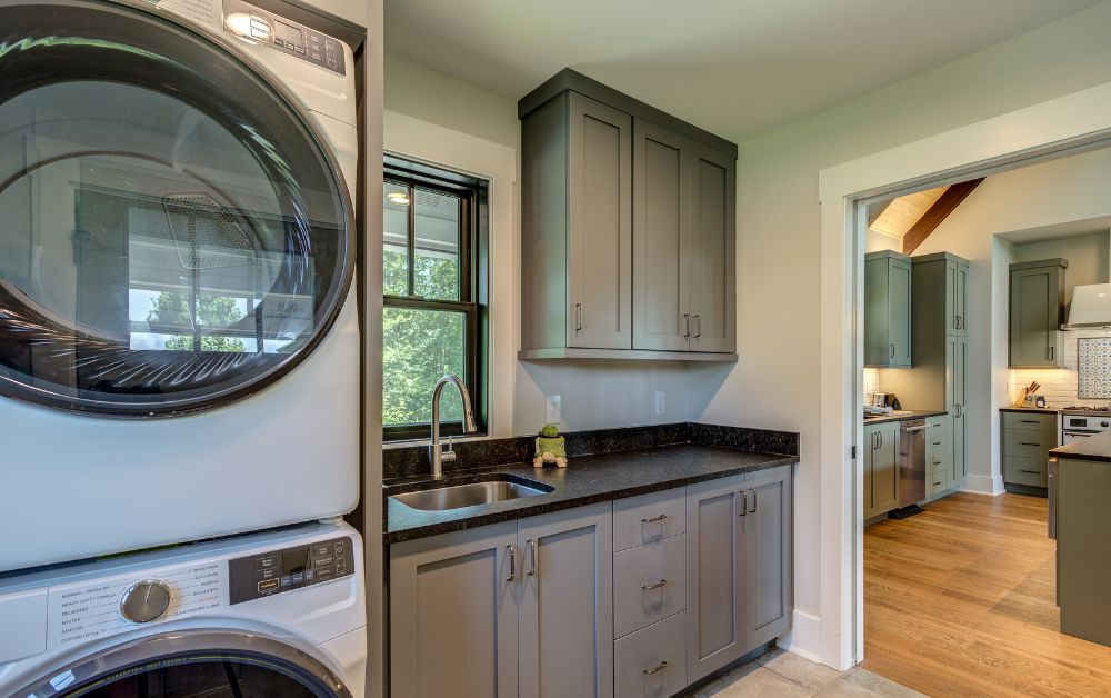 Functional laundry room with custom cabinetry, utility sink, and direct access to the kitchen.