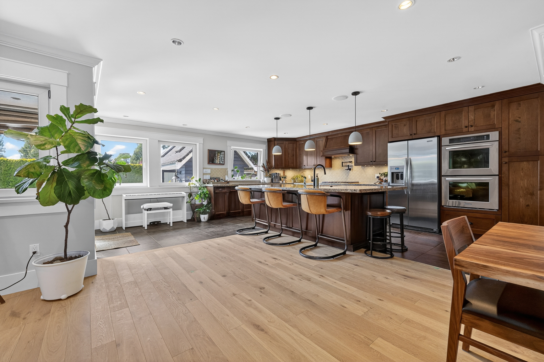 Open-concept kitchen in a Delta, BC custom home with dark wood cabinetry, large island, and bar seating.